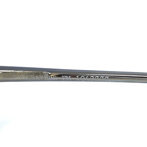 Puede incluir: Primer plano del brazo de unas gafas con el texto "SPECSAVERS FM 10/3229" grabado en el metal.