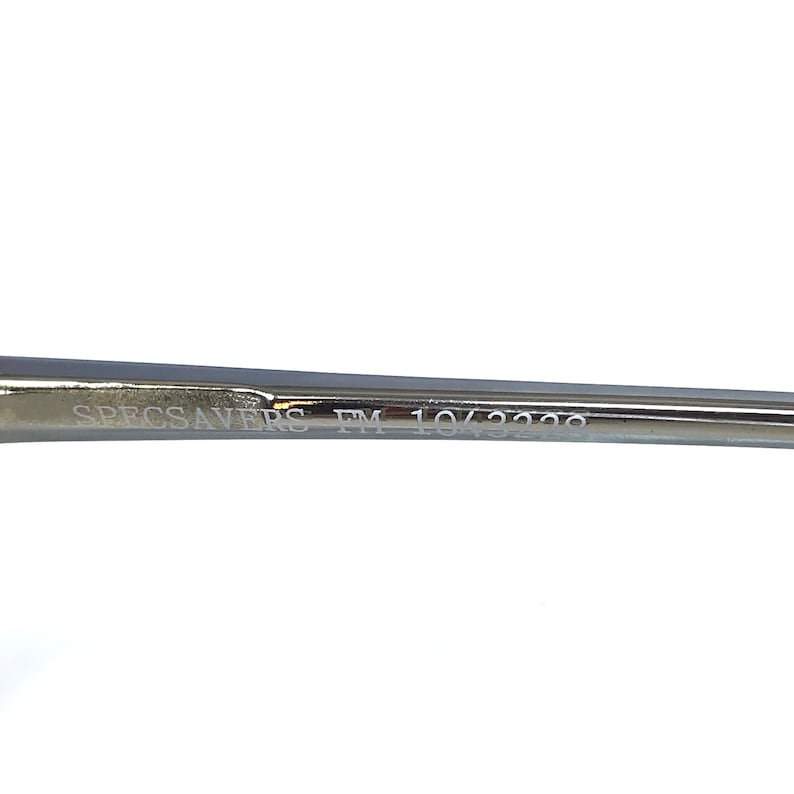 Puede incluir: Primer plano del brazo de unas gafas con el texto "SPECSAVERS FM 10/3229" grabado en el metal.