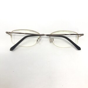 May include: A pair of silver-toned eyeglasses with black arms and clear lenses.