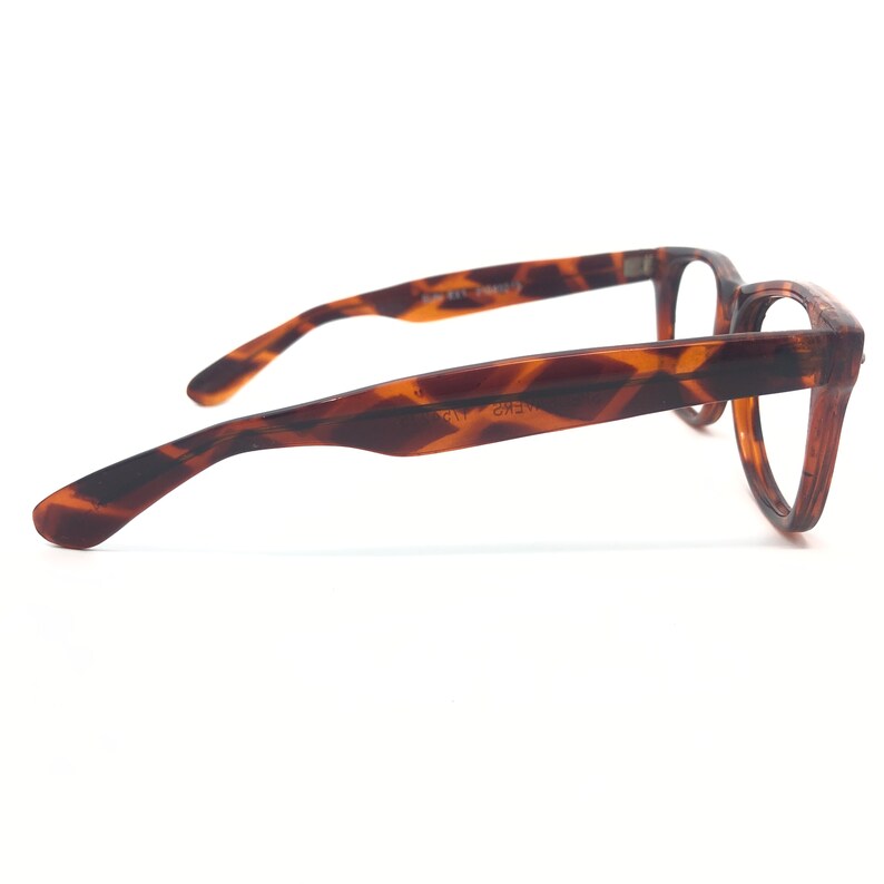 K&ouml;nnte beinhalten: Braune Brille mit Schildpattmuster und klassischem Rahmendesign. Die Brille hat eine rechteckige Form und besteht aus einem strapazierf&auml;higen Material. Die B&uuml;gel der Brille sind sanft gebogen, um bequem hinter den Ohren zu sitzen. Die Gl&auml;ser sind klar.