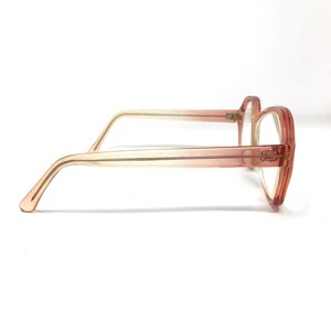 May include: A pair of pink plastic eyeglasses with a gradient fade from light pink to a darker pink. The glasses have a rounded rectangular shape.