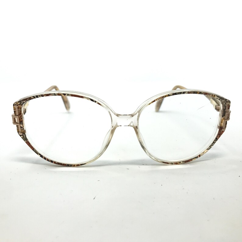 May include: Clear plastic eyeglasses with a brown and gold patterned frame.