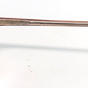May include: Close-up of a pair of eyeglasses with a light brown frame. The text "SPECSAVERS 1750199" is printed on the frame. The background is white.