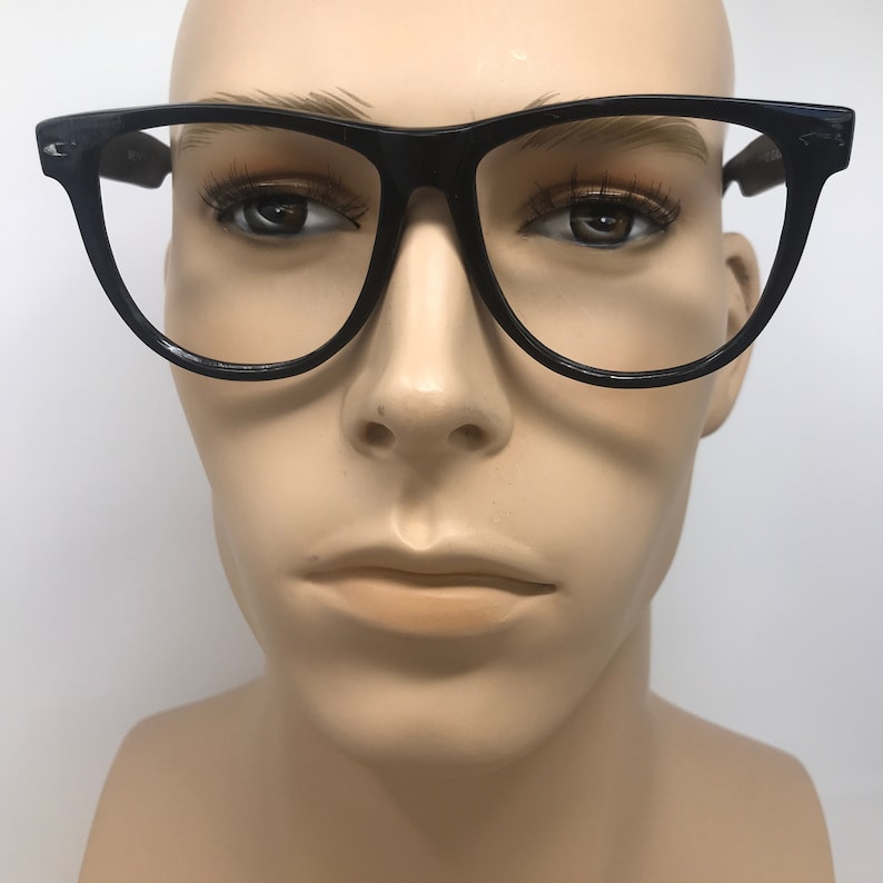 May include: Black, thick-framed eyeglasses with a classic design. The frames are a solid black color, and the lenses are clear. The glasses are displayed on a mannequin head.