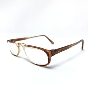 May include: Brown plastic framed eyeglasses with clear lenses. The glasses have a simple, classic design.