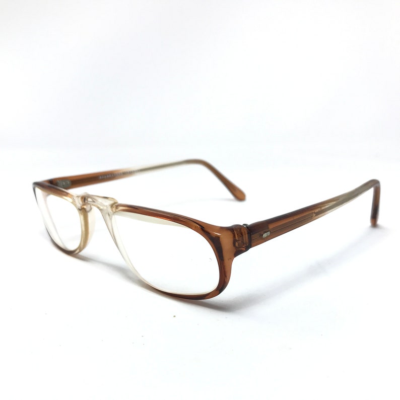 May include: Brown plastic framed eyeglasses with clear lenses. The glasses have a simple, classic design.