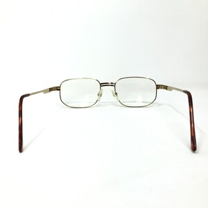 May include: Gold-tone metal rectangular eyeglasses with brown tortoise shell temple arms.