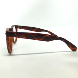 May include: Brown tortoiseshell eyeglasses with a rectangular frame. The arms of the glasses have a diamond pattern. The glasses are set against a white background.