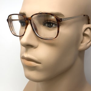 K&ouml;nnte beinhalten: Eine Brille mit Schildpatt-Gestell, klaren Gl&auml;sern und einem silbernen Metallrahmen.