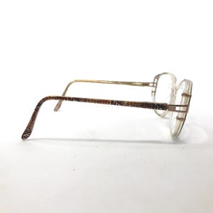 May include: A pair of gold-tone eyeglasses with brown patterned arms and clear lenses.