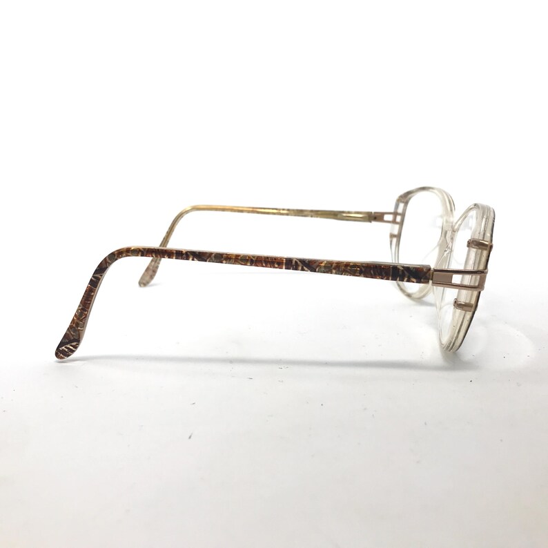 May include: A pair of gold-tone eyeglasses with brown patterned arms and clear lenses.