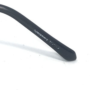 May include: Close-up of the black arm of a pair of glasses with the text "Specsavers 1.5..." printed on the arm.