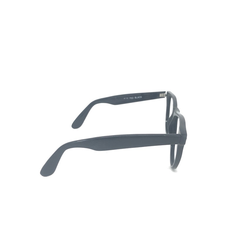 May include: Black eyeglasses with a rectangular frame. The temples are thick and curve down to the ear. The text "F-W 932 BLACK" is printed on the temple. The glasses are set against a white background.