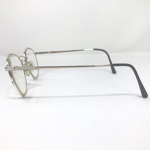 Peut inclure: Lunettes &agrave; monture argent&eacute;e avec verres ronds. Les lunettes ont une monture fine argent&eacute;e avec un pont et des plaquettes nasales. Les branches sont argent&eacute;es et passent au noir aux extr&eacute;mit&eacute;s. Les verres sont clairs.