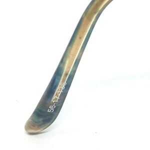 May include: Close-up of a portion of eyeglasses arm. The arm is a gradient of blue and gold, with the text "56-17-135" printed in white. The glasses arm curves gently against a white background.