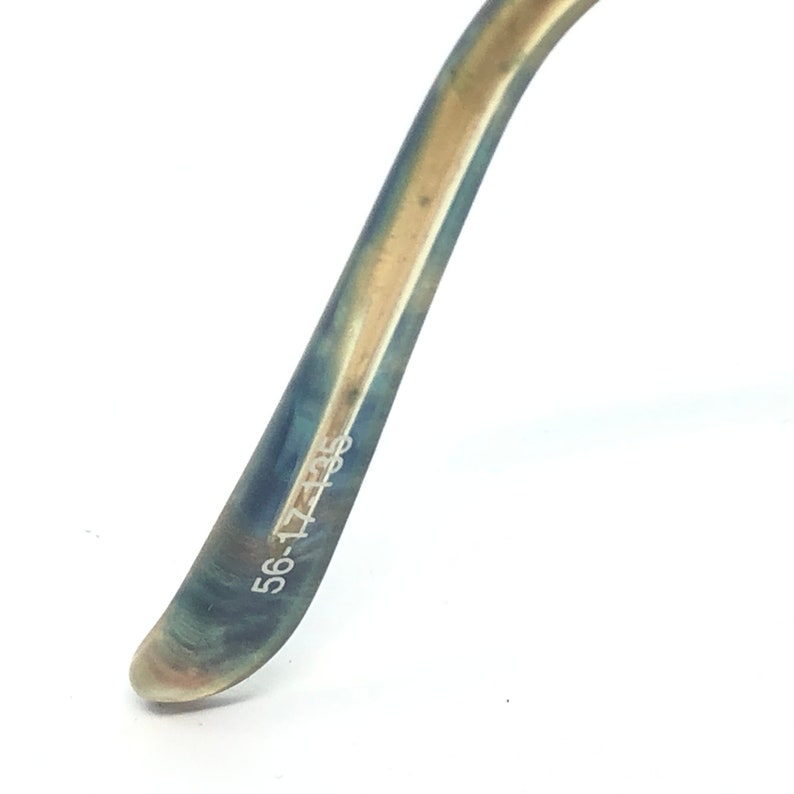 May include: Close-up of a portion of eyeglasses arm. The arm is a gradient of blue and gold, with the text "56-17-135" printed in white. The glasses arm curves gently against a white background.