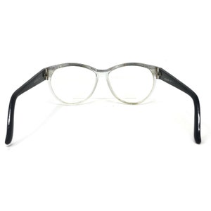 May include: Clear eyeglasses with a rounded frame and black temples. The frame has a speckled design along the top. The lenses are clear, and the glasses are open, displaying the interior of the frame.