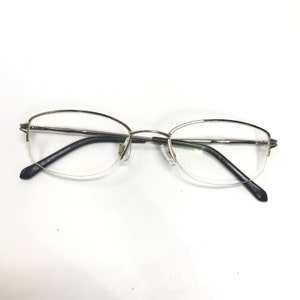 May include: Gold-rimmed eyeglasses with clear lenses and black temple arms. The arms are marked "MADE IN CHINA".