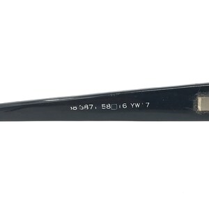 May include: Black eyeglass frame arm with the numbers and letters: 58587, 58 16 YW'7. The frame is glossy and rectangular. The arm is angled slightly upward.