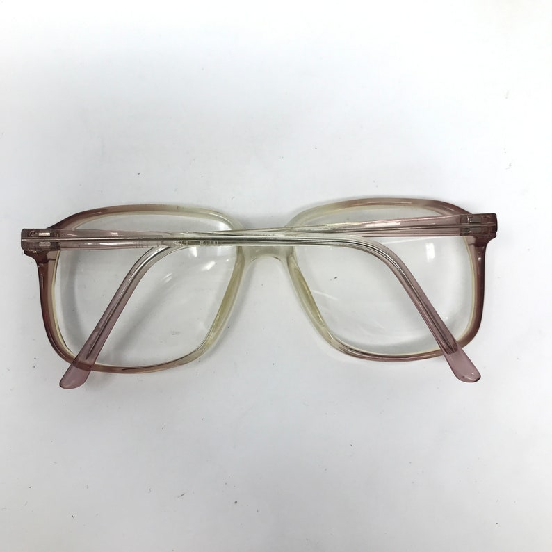 May include: Clear eyeglasses with a light brown and purple frame. The glasses have a rectangular shape and are viewed from above. The lenses are clear, and the arms are a light purple color.