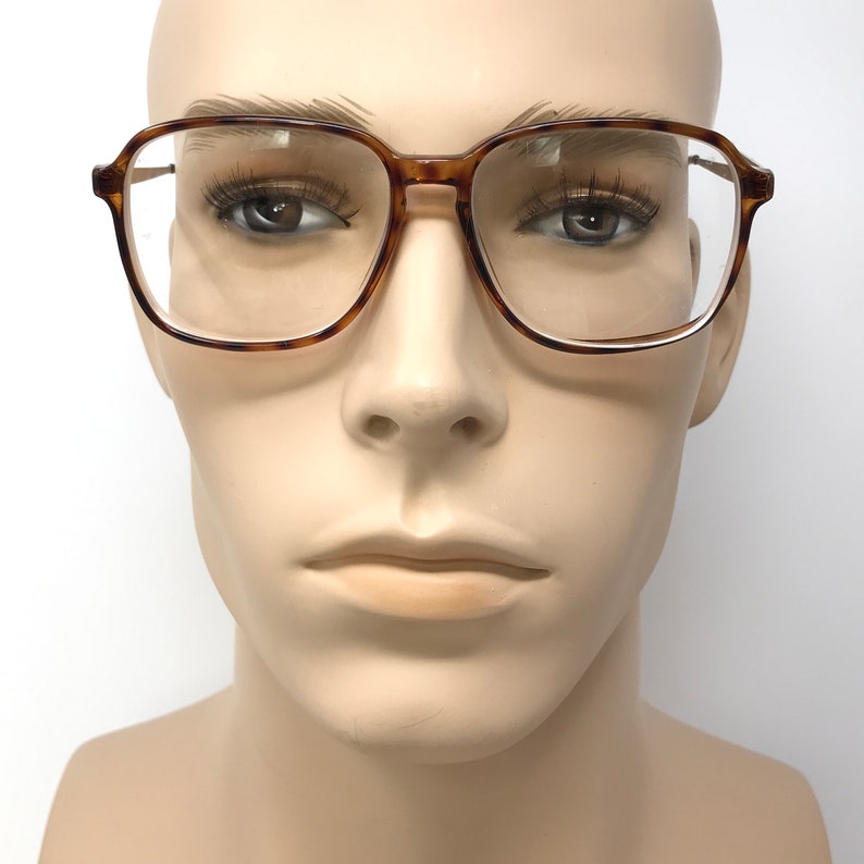 K&ouml;nnte beinhalten: Eine Brille aus braunem Schildpatt mit klaren Gl&auml;sern. Die Brille hat eine quadratische Form und befindet sich auf einem Mannequin-Kopf.