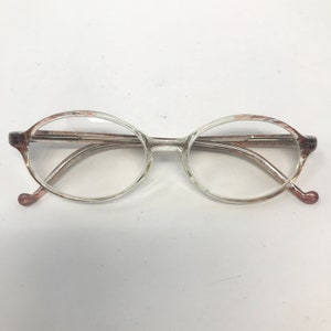 May include: Oval-shaped spectacles with clear frames and brown patterned accents on the temples. The lenses are clear, and the arms have a subtle curve. The design is simple and classic.
