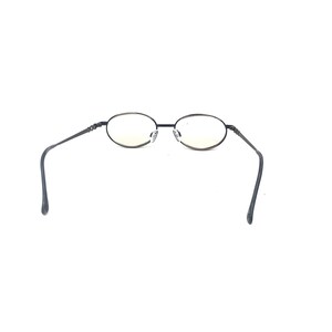 May include: Oval-shaped eyeglasses with a black metal frame. The lenses are clear with a slight yellow tint. The temples are thin and extend outward, curving at the ends. The glasses are set against a white background.