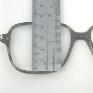 Puede incluir: Primer plano de gafas con estampado de carey. Se coloca una regla met&aacute;lica junto a la montura, midiendo aproximadamente 5 cm de altura. Las gafas tienen forma cuadrada y est&aacute;n sobre un fondo blanco.