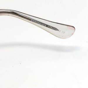 K&ouml;nnte beinhalten: Nahaufnahme des B&uuml;gels einer Brille. Der Rahmen ist aus silberfarbenem Metall. Der Text "Specsavers 175428M ce" ist auf der Innenseite des B&uuml;gels aufgedruckt.