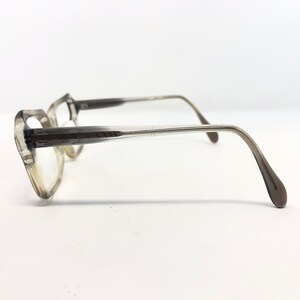 Op de afbeelding: Een vintage bril met een lichtbruin verlopend montuur. De glazen zijn helder en de pootjes van de bril hebben een subtiele curve. De bril staat tegen een witte achtergrond.