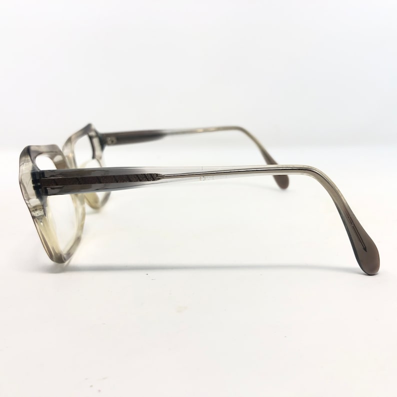 Op de afbeelding: Een vintage bril met een lichtbruin verlopend montuur. De glazen zijn helder en de pootjes van de bril hebben een subtiele curve. De bril staat tegen een witte achtergrond.