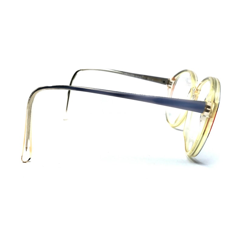Puede incluir: Un par de gafas redondas con montura transparente y patillas azules. Las gafas son de pl&aacute;stico y tienen un estilo vintage.
