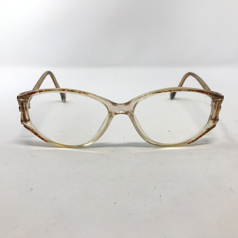 May include: Clear-framed eyeglasses with a light brown tint. The frames have a rectangular shape with rounded edges. The temples and the edges of the frames have a brown and orange pattern. The glasses are set against a white background.