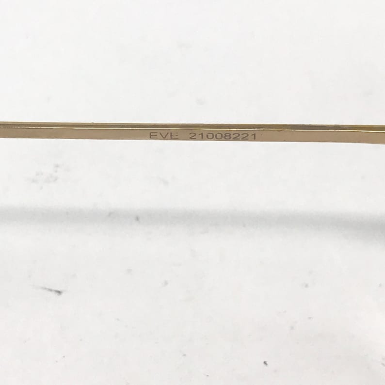 Pu&ograve; includere: Primo piano di una barra di metallo dorata con il testo "EVL 21008221" inciso su di essa.