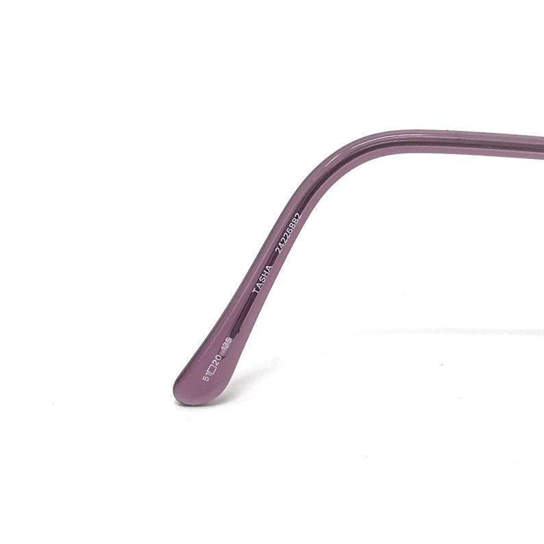 Puede incluir: Primer plano de una patilla de gafas de color lavanda. La patilla tiene el texto "TASHA 24226882" impreso. La talla de la montura es 51☐20 135.