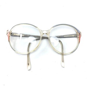 Puede incluir: Gafas de pl&aacute;stico transparente con montura azul claro y un acento rojo en el lateral. Las gafas tienen lentes redondas.