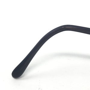 May include: Close-up of a black eyeglass arm. The arm curves gently and ends in a rounded tip. The surface appears smooth and glossy, with a slight reflection.