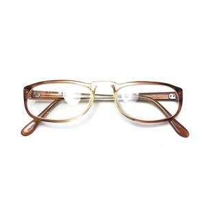 May include: Brown and gold-toned eyeglasses with clear lenses. The glasses have a rectangular shape and a thin metal bridge.