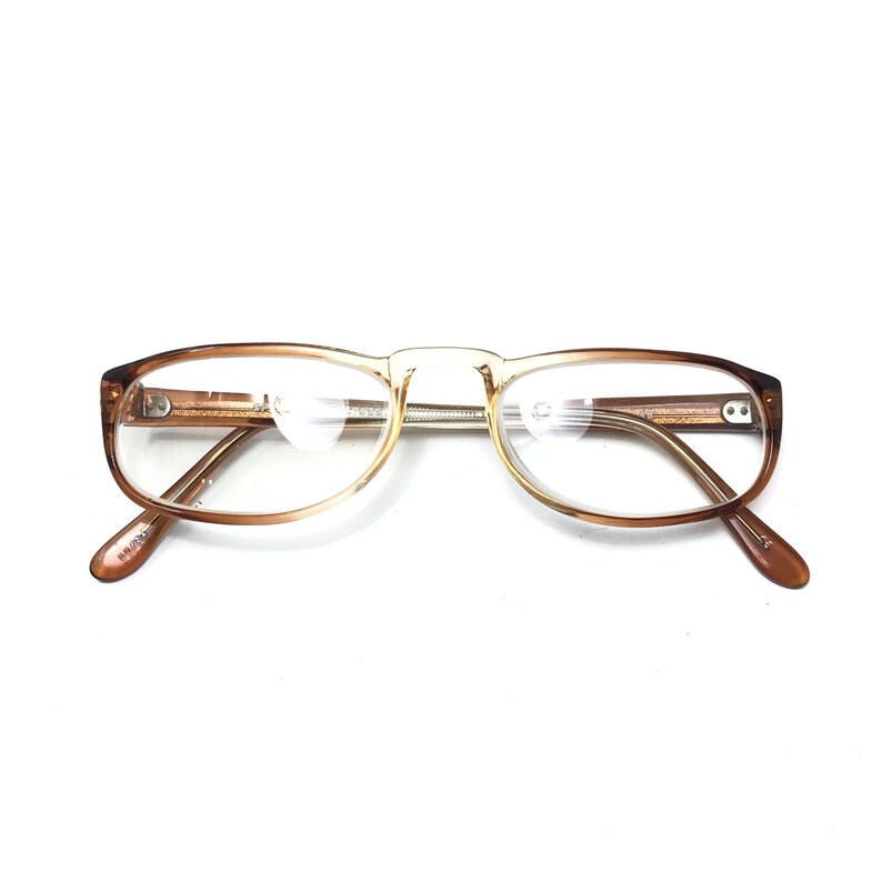 May include: Brown and gold-toned eyeglasses with clear lenses. The glasses have a rectangular shape and a thin metal bridge.