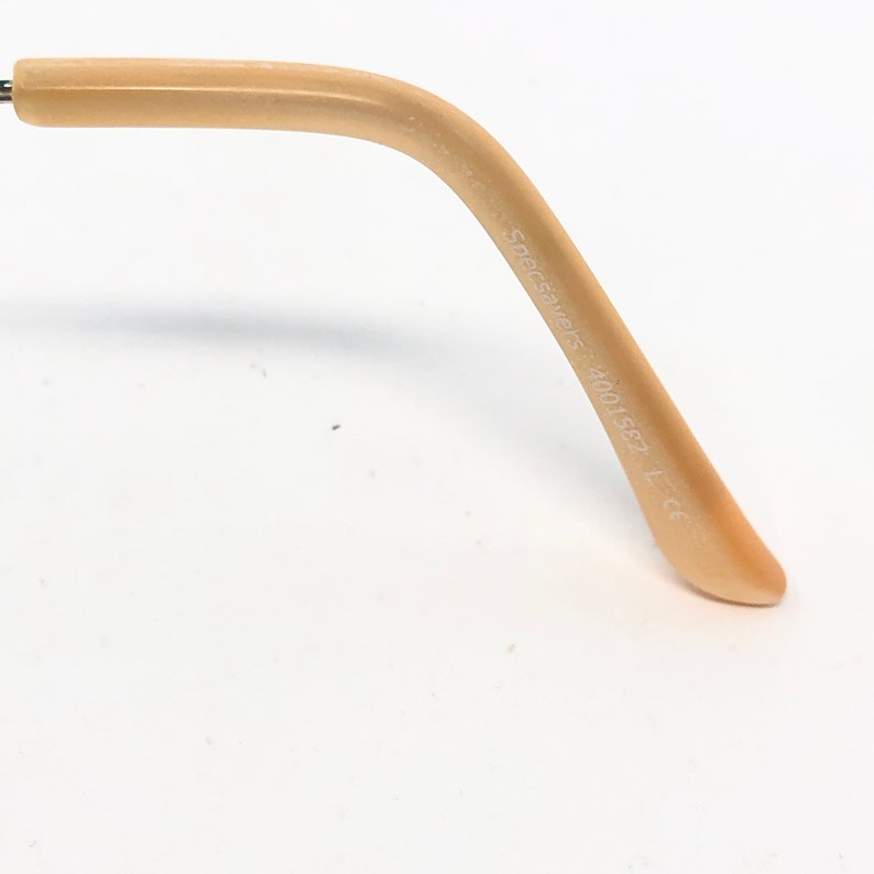 May include: Close-up of a light beige eyeglass arm. The arm curves gently and has the text "Specsavers 4001582" printed on it. The arm is made of a smooth material and is set against a white background.