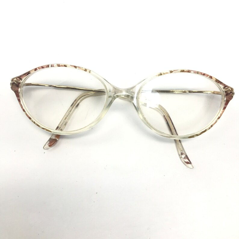 May include: Clear oval-shaped eyeglasses with a brown and white patterned frame.