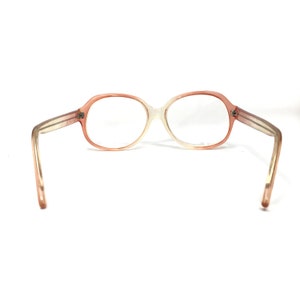 May include: A pair of pink and white oval-shaped eyeglasses with clear lenses.