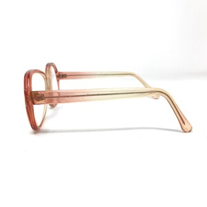 May include: A pair of pink and clear plastic eyeglasses with a rounded frame.