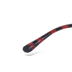 May include: Close-up of the arm of eyeglasses with a tortoiseshell pattern in shades of brown and black. The text "JOHN 21660641 54018-145" is printed in white.