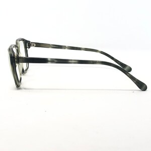 May include: A pair of eyeglasses with a gray and black marbled pattern. The frames are thick and rectangular, with a subtle cat-eye shape. The temples are thin and curve down to the ear. The lenses are clear.