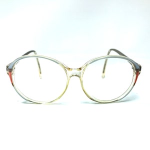 Puede incluir: Gafas redondas de pl&aacute;stico transparente con ribete marr&oacute;n y naranja.