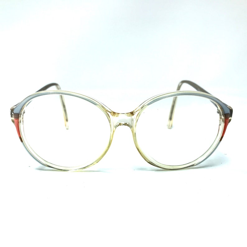 Puede incluir: Gafas redondas de pl&aacute;stico transparente con ribete marr&oacute;n y naranja.