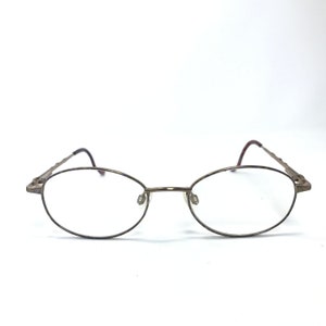 May include: A pair of oval-shaped, gold-toned spectacles with thin metal frames.