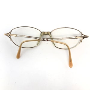 Peut inclure: Lunettes en m&eacute;tal dor&eacute; avec des verres de forme ovale et une monture fine en fil m&eacute;tallique. Les branches sont en plastique beige.