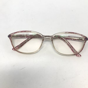 May include: Clear eyeglasses with a rectangular frame and red and white striped accents on the temples. The lenses are clear, and the frame is a light, transparent color. The glasses are set against a white background.